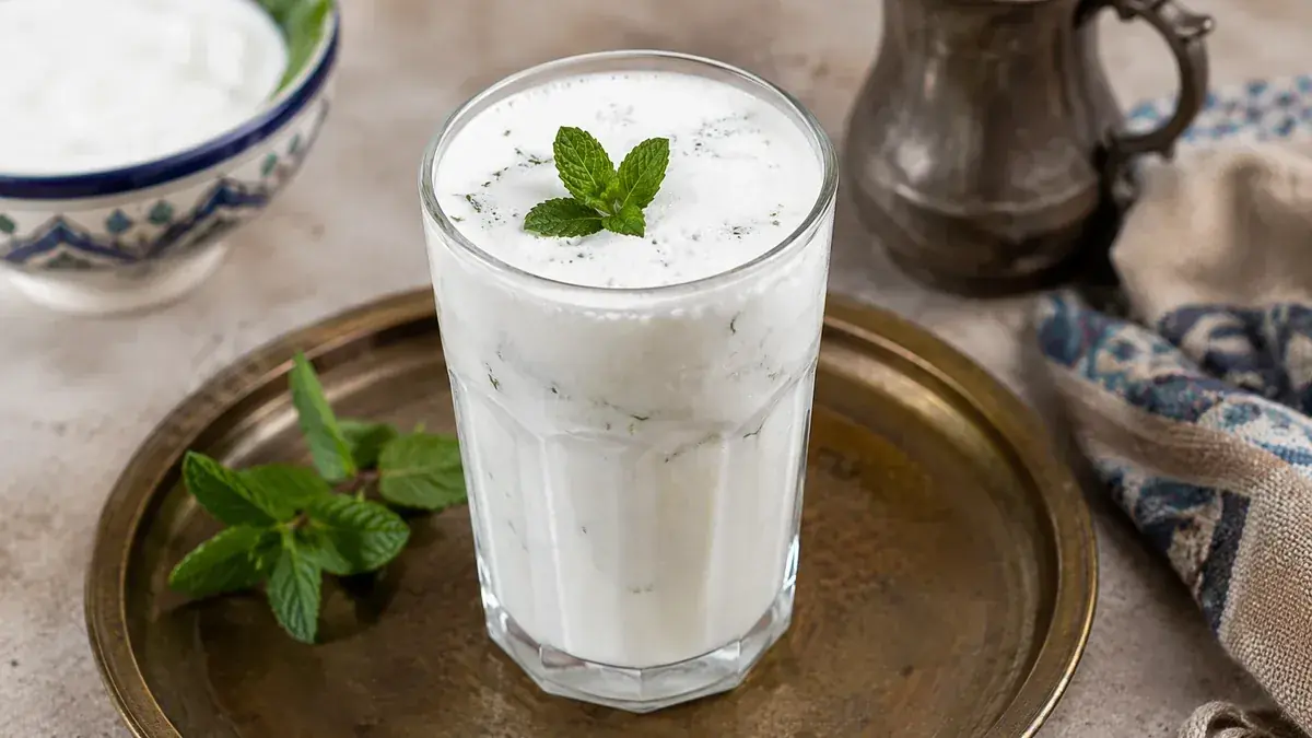 Chilled Lebanese-style Ayran yogurt drink in a clear glass with ice and fresh mint.
