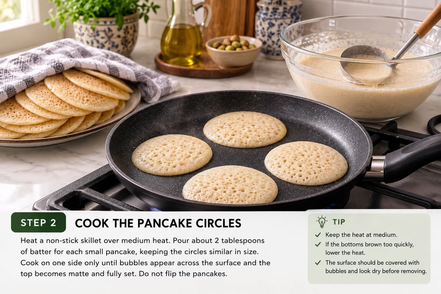 Small atayef pancakes cooking on one side in a non-stick skillet.