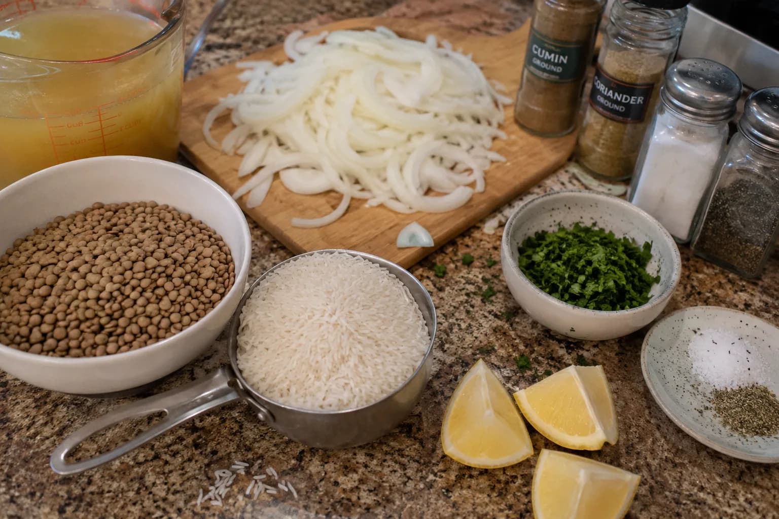 Brown lentils, rinsed long-grain rice, sliced onions, spices, vegetable broth, parsley, and lemon prepared for Mujadara.