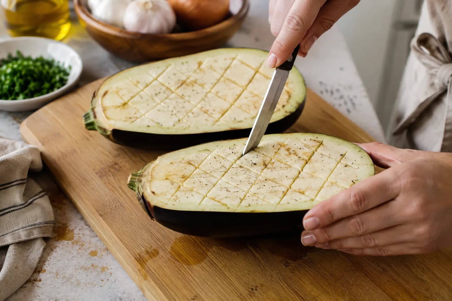 Halved eggplants scored in a shallow crisscross pattern before roasting.